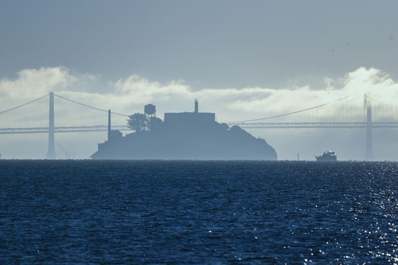 Un barco se dirige a la isla de Alcatraz mientras al fondo se puede ver el Puente de la Bahía de San Francisco-Oakland, en esta imagen del 13 de diciembre de 2023 tomada desde Sausalito, California. (AP Foto/Eric Risberg, Archivo)
