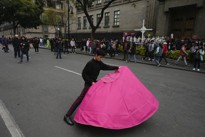Juan Pablo Vargas hace movimientos del toreo con un capote en una protesta en la que defensores y críticos de las corridas de todos se reunieron a las afueras de la Suprema Corte, en Ciudad de México, el miércoles 6 de diciembre de 2023. La Suprema Corte de México tenía previsto decidir si reactivaba las corridas en la capital, un año después de que fueran prohibidas. (AP Foto/Fernando Llano)