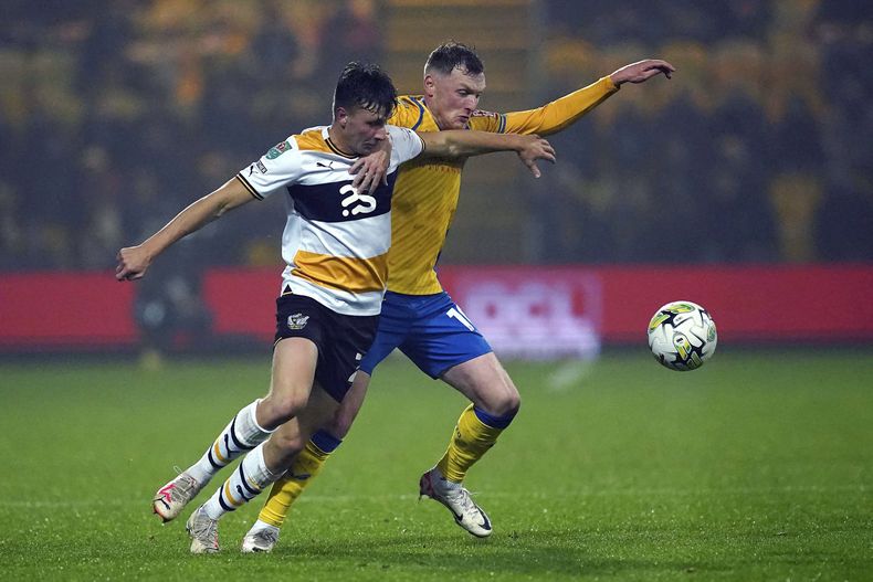 James Plant (izquierda), de Port Vale, y George Maris, de Mansfield Town, disputan un balón en un partido de la Copa de la Liga Inglesa, el martes 31 de octubre de 2023 (Martin Rickett/PA via AP)