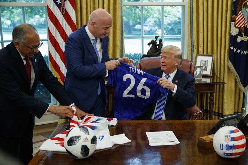 ARCHIVO - El presidente de la Federación Estadounidense de Fútbol, Carlos Cordeiro (izquierda), y el presidente de la FIFA, Gianni Infantino, entregan camisetas de fútbol al presidente Donald Trump durante una reunión en la Oficina Oval de la Casa Blanca, el martes 28 de agosto de 2018, en Washington. (Foto AP/Evan Vucci, Archivo)
