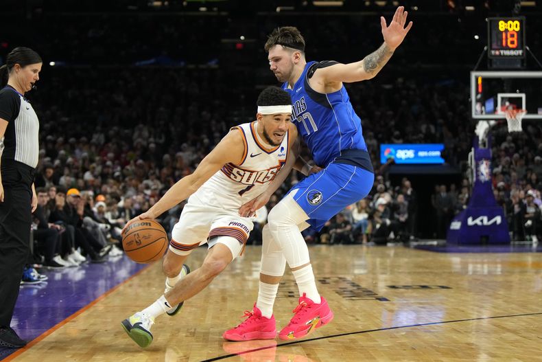 Devin Booker, de los Suns de Phoenix, esquiva a Luka Doncic, de los Mavericks de Dallas, en el partido de la NBA, el lunes 25 de diciembre de 2023, en Phoenix. (Foto AP/Rick Scuteri)