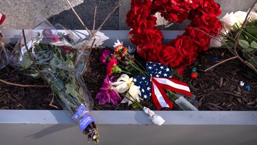 Un pequeño monumento hecho con banderas, flores y otros objetos en una jardinera, el viernes 28 de noviembre de 2025, cerca del sitio donde dos miembros de la Guardia Nacional fueron tiroteados en Washington. (AP Foto/Mark Schiefelbein)