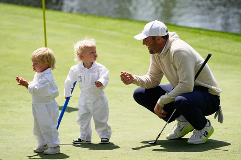 Scottie Scheffler (derecha) interactua con su hijo Bennett (centro) mientras que Bear, el hijo de Sam Burn, come golosinas durante una práctica previo al Masters de golf, el miércoles 8 de abril de 2026, en Augusta, Georgia. (AP Foto/Gerald Herbert)