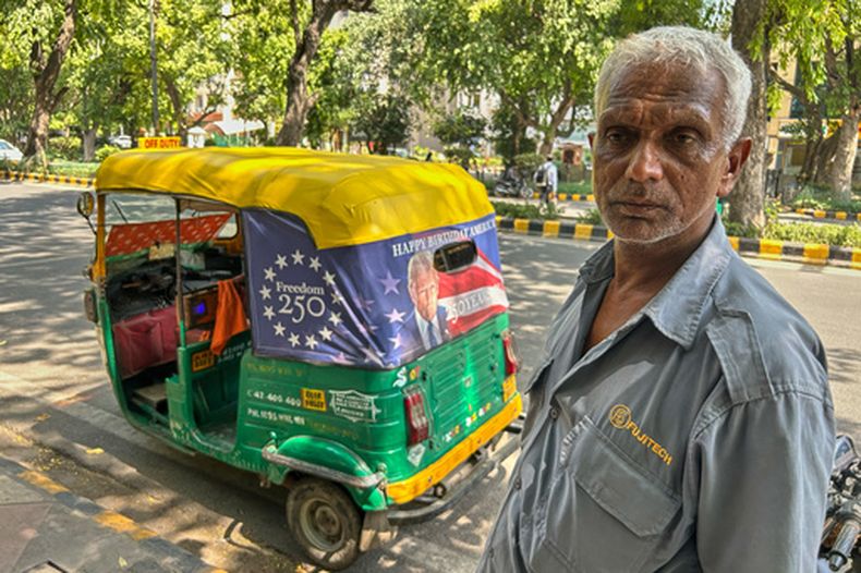 Ganesh Kumar se ve junto a su rickshaw motorizado, con una lona con la imagen del presidente de Estados Unidos, Donald Trump, que celebra 250 años de Estados Unidos en la parte trasera de su vehículo en Nueva Delhi, India, el 20 de mayo de 2026. (AP Foto/Piyush Nagpal)