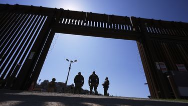 Agentes de la Patrulla Fronteriza y efectivos militares se detienen dentro de una puerta en uno de los dos muros fronterizos que separan México de Estados Unidos durante una conferencia de prensa sobre las operaciones conjuntas en las que participan militares y la Patrulla Fronteriza, el viernes 21 de marzo de 2025, en San Diego. (AP foto/Gregory Bull)