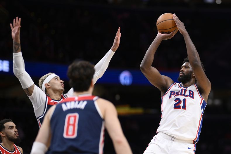 El pívot de los 76ers de Filadelfia Joel Embiid lanza el balón entre los aleros Kyle Kuzma y Dani Avdija de los Wizards de Washington en el encuentro del miércoles 6 de diciembre del 2023. (AP Foto/Nick Wass)