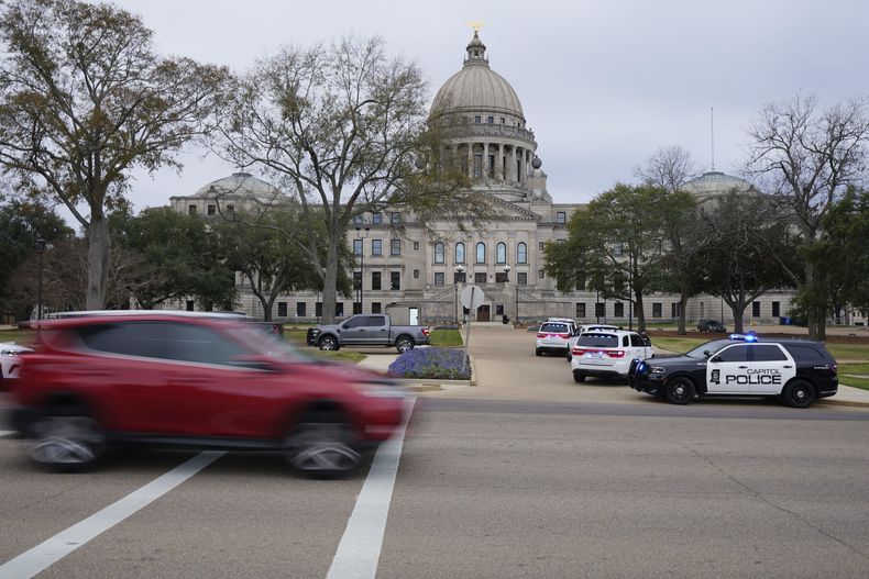 Automóviles pasan frente al Capitolio de Mississippi, en Jackson, Mississippi, mientras la Policía del Capitolio responde a una amenaza de bomba dentro del edificio, el miércoles 3 de enero de 2024. (AP Foto/Rogelio V. Solis)