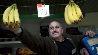 americateve | Un vendedor ambulante cuelga bananas con el precio en rulos y hryvnias en Simferopol, Crimea, el mi&eacute;rcoles, 26 de marzo del 2014. (Foto AP/Pavel Golovkin)