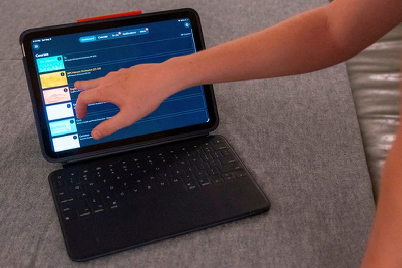 El hijo de LuAnn Oliver demuestra cómo usa un iPad para sus clases en una reunión en la que un grupo de padres de alumnos analizaron formas de oponerse al tiempo en pantalla en las escuelas de sus hijos, el sábado 9 de mayo de 2026 en Arlington, Virginia. (AP Foto/Kevin Wolf)