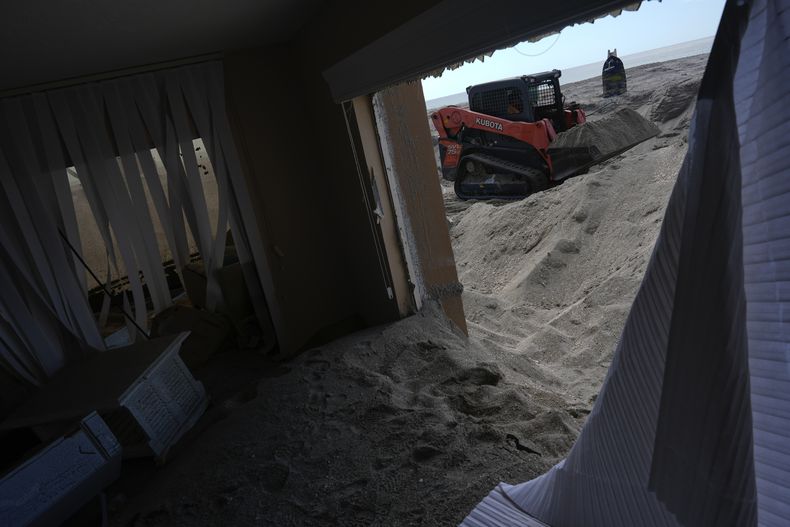 Scott Bennett, un contratista que se especializa en recuperación tras el paso de tormentas, quita arena del patio de un condominio playero en Venice, Florida, tras el paso del huracán Milton, el sábado 12 de octubre de 2024. (AP Foto/Rebecca Blackwell)