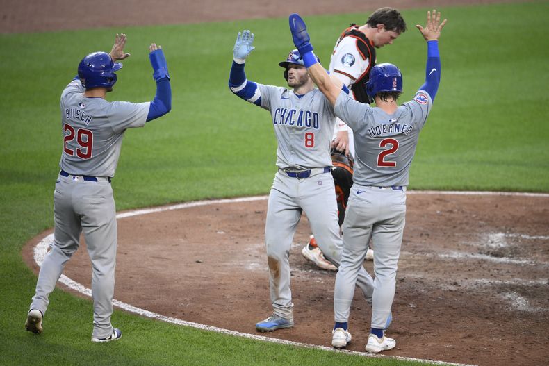 Ian Happ (8) de los Cachorros de Chicago celebra su cuadrangular de tres carreras junto a sus compañeros de equipo Nico Hoerner (23) y Michael Busch (29) durante el cuarto capítulo del juego de béisbol ante los Orioles de Baltimore, el martes 9 de julio de 2024, en Baltimore. (AP Foto/Nick Wass)