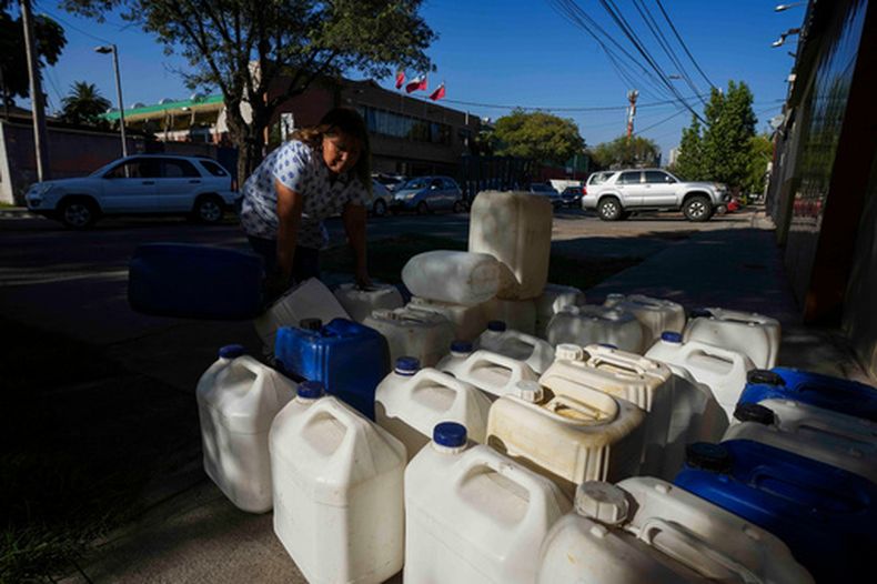 Una mujer vende tanques de gasolina portátiles mientras los conductores hacen fila para llenar sus tanques en Santiago de Chile, el martes 24 de marzo de 2026. (Foto AP/Esteban Félix)