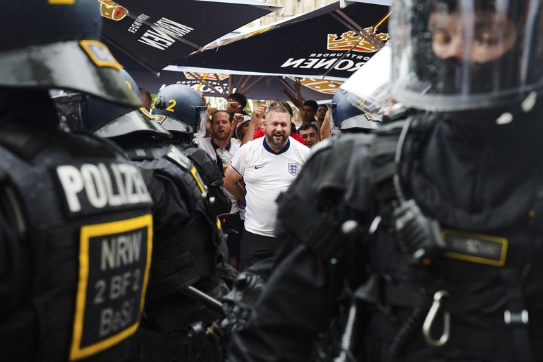 ARCHIVO - Hinchas de Inglaterra hablan con agentes de policía mientras celebran antes de un partido de semifinales entre Holanda e Inglaterra en la Eurocopa 2024 en Dortmund, Alemania, el miércoles 10 de julio de 2024. El principal funcionario de seguridad de Alemania dijo que las autoridades tuvieron menos problemas de seguridad y delitos con los que lidiar de lo que esperaban en la Eurocopa. El torneo terminó el domingo con España venciendo a Inglaterra 2-1 en la final en Berlín y sin informes de disturbios graves. (AP Foto/Markus Schreiber, Archivo)