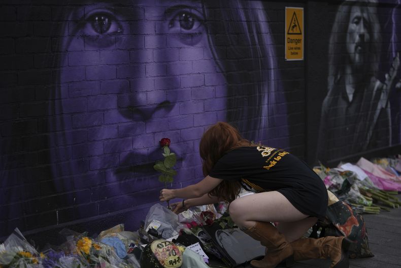 Una fan coloca una flor para conmemorar la muerte de Ozzy Osbourne en Birmingham, Inglaterra, el miércoles 23 de julio de 2025. (Foto AP/Kin Cheung)