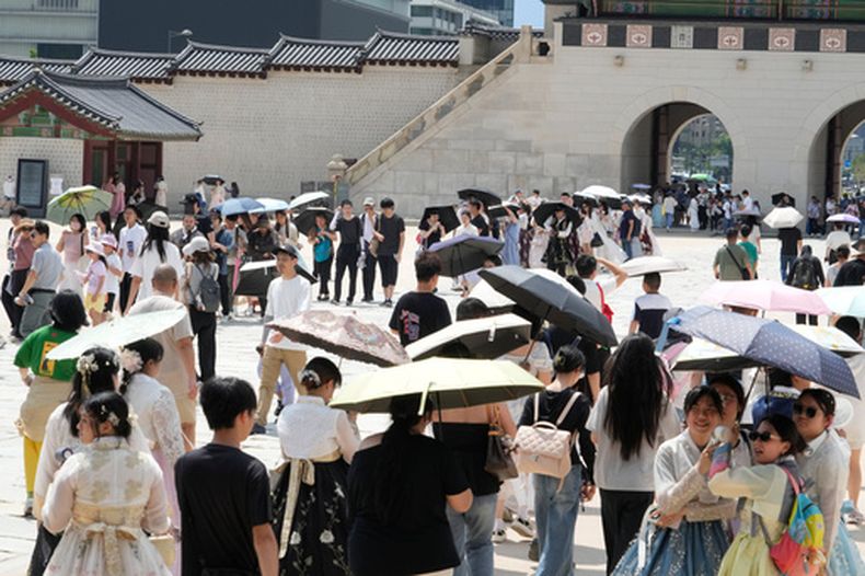 Visitantes se protegen del sol con paraguas en el Palacio Gyeongbok, en Seúl, Corea del Sur, el 5 de agosto de 2026. (AP Foto/Ahn Young-joon)