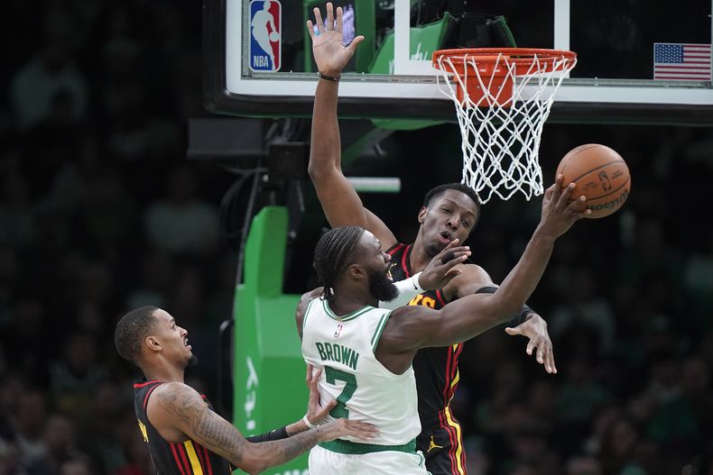 Jaylen Brown (7), de los Celtics de Boston, pasa el balón ante el intento de quitárselo de Dejounte Murray, izquierda, y Onyeka Okongwu, derecha, en la segunda mitad del juego de baloncesto de la NBA, el domingo 26 de noviembre de 2023, en Boston. (AP Foto/Steven Senne)