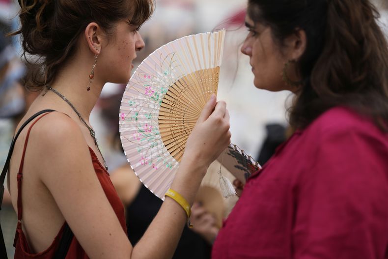 Manifestantes utilizan abanicos para aliviar el calor durante una protesta contra la crisis de vivienda en Portugal, en Lisboa, el sábado 28 de junio de 2025. (AP Foto/Armando Franca)