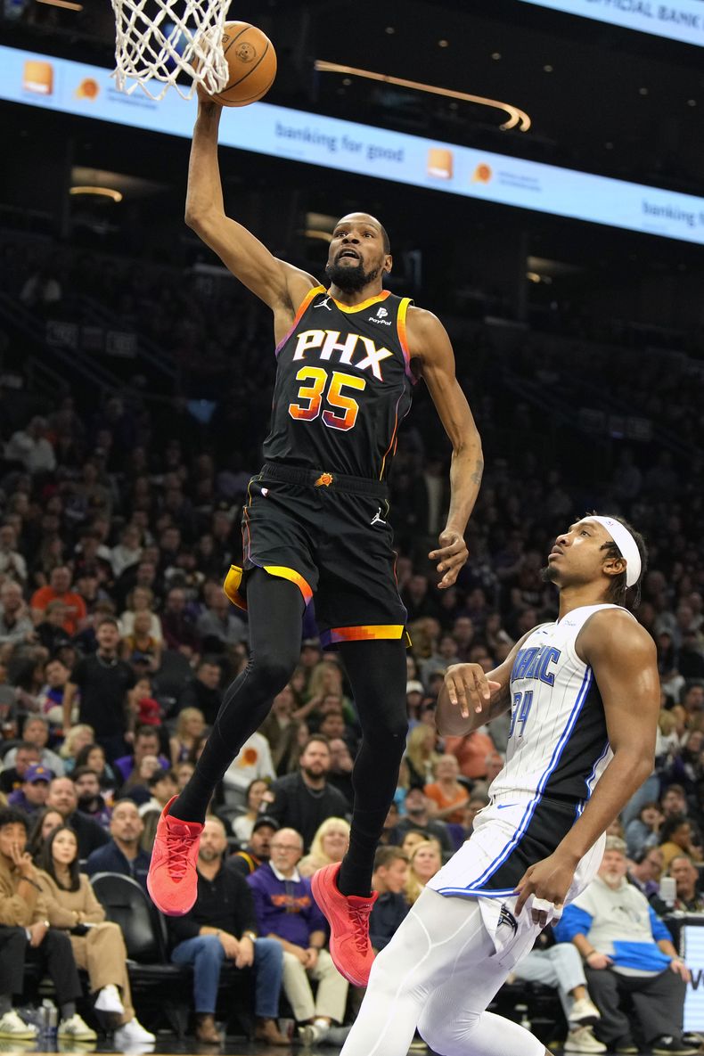 Kevin Durant (35), alero de los Suns de Phoenix, retaca el balón sobre el pívot del Magic de Orlando, Wendell Carter Jr., durante la primera mitad del juego de baloncesto de la NBA, el domingo 31 de diciembre de 2023, en Phoenix. (AP Foto/Rick Scuteri)