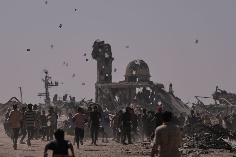 Palestinos recogen panfletos arrojados por un dron israelí, que advierten a la gente que se mantenga alejada de la llamada línea amarilla en Jan Yunis, en el sur de la Franja de Gaza, el lunes 20 de octubre de 2025. (AP Foto/Jehad Alshrafi)