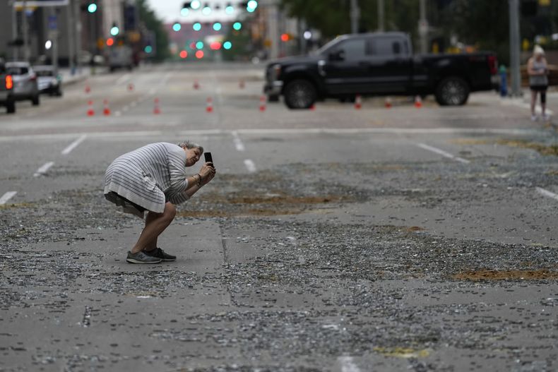 Cheryl Herpich toma una foto de un edificio del centro de la ciudad con las ventanas reventadas tras una fuerte tormenta eléctrica, el viernes 17 de mayo de 2024, en Houston. (AP Foto/David J. Phillip)