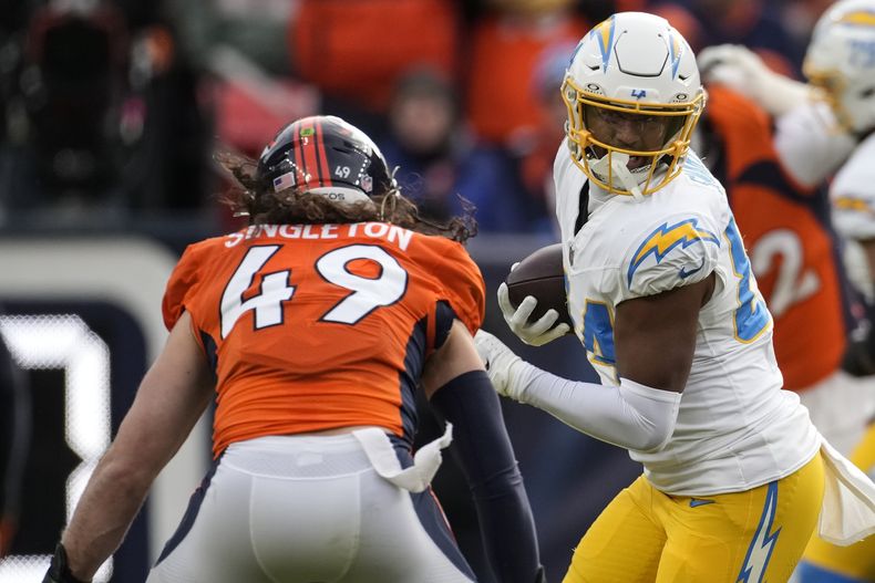 Stone Smartt (84), tight end de los Chargers de Los Ángeles, corre después de recibir un pase y encara a Alex Singleton (49), linebacker de los Broncos de Denver, durante la primera mitad del juego de la NFL, el domingo 31 de diciembre de 2023, en Denver. (AP Foto/David Zalubowski)