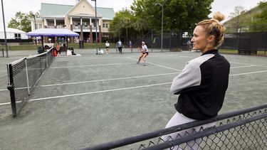Iris Harris se recarga en una cerca mientras observa una práctica en el torneo de Charleston, el 3 de abril de 2023. Harris es integrante del Programa de Inclusión de Entrenadoras (AP Foto/Mic Smith)