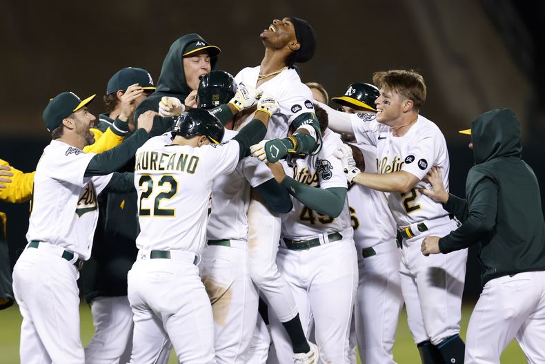 Esteury Ruiz (centro), de los Atléticos de Oakland, celebra con sus compañeros la victoria tras sacudir el sencillo del triunfo en el 12mo inning del juego de la MLB que enfrentó a su equipo con los Diamondbacks de Arizona, en Oakland, California, el 16 de mayo de 2023. (AP Foto/Jed Jacobsohn)