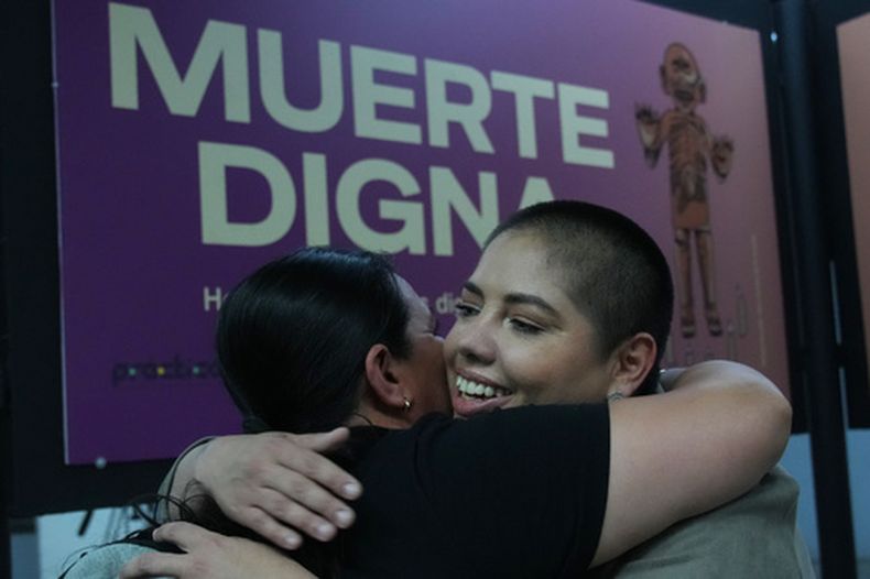 Samara Martínez, defensora de una ley para despenalizar la eutanasia, abraza a una amiga durante la exposición Muerte Digna en la estación de metro Ermita en la Ciudad de México, el lunes 23 de marzo de 2026. (AP Foto/Marco Ugarte)