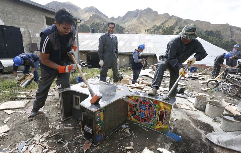 Trabajadores usan mazas para destruir m&aacute;quinas tragamonedas que fueron confiscadas tres a&ntilde;os atr&aacute;s a casas de juego ilegales el viernes 28 de octubre de 2014 en La Paz, Bolivia. (AP foto/Juan Karita)