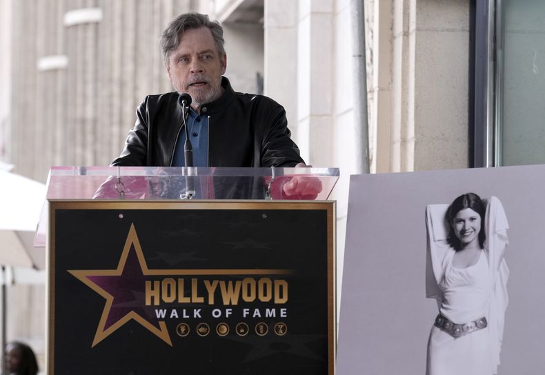 Mark Hamill habla durante una ceremonia en honor a la fallecida actriz Carrie Fisher, en una fotografía a la derecha, durante una ceremonia para develar su estrella póstuma en el Paseo de la Fama de Hollywood en Los Ángeles el jueves 4 de mayo de 2023. La fecha se conoce también como Día de Star Wars, en homenaje a las películas de Star Wars en las que Fisher interpretó a la Princesa Leia. (Foto AP/Chris Pizzello)