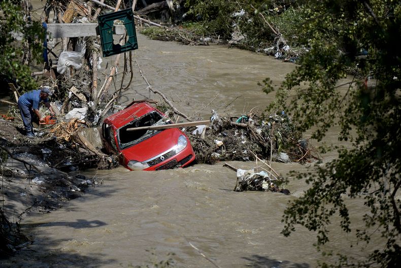 Un hombre corta troncos con una sierre el&eacute;ctrica para liberar un veh&iacute;culo que fue arrastrada por las aguas cerca de la ciudad de Bascov, en Rumania, el mi&eacute;rcoles 30 de julio de 2014. (Foto de AP/Octav Ganea, Mediafax)