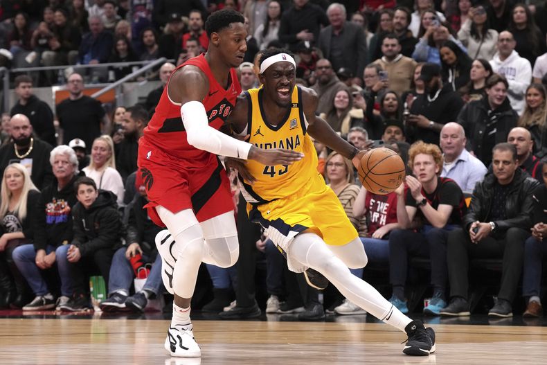 Pascal Siakam, de los Pacers de Indiana, elude a RJ Barrett, de los Raptors de Toronto, durante el duelo del miércoles 14 de febrero de 2024 (Chris Young/The Canadian Press via AP)