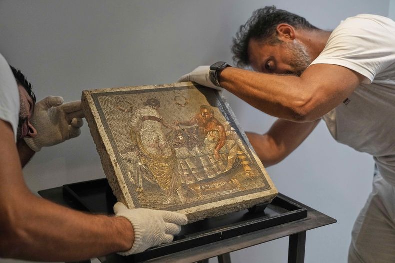 Restauradores exhiben un mosaico romano que representa a una pareja de amantes, que fue repatriado desde Alemania, en el parque arqueológico de Pompeya, Italia, el martes 15 de julio de 2025. (Foto AP/Gregorio Borgia)