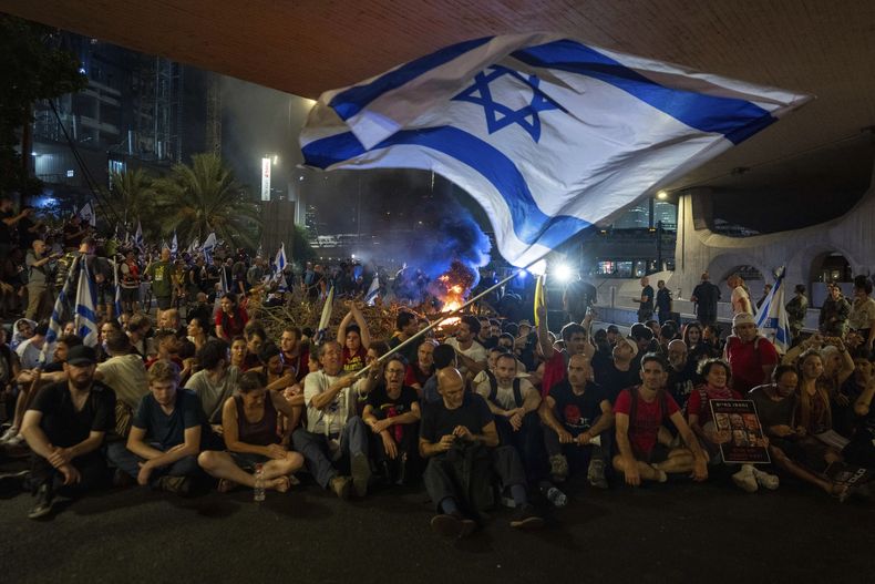 Personas bloquean un camino durante una protesta para exigir un acuerdo que lleve a la liberación inmediata de los rehenes que mantiene Hamás en la Franja de Gaza, el domingo 1 de septiembre de 2024, en Tel Aviv, Israel. (AP Foto/Ohad Zwigenberg)