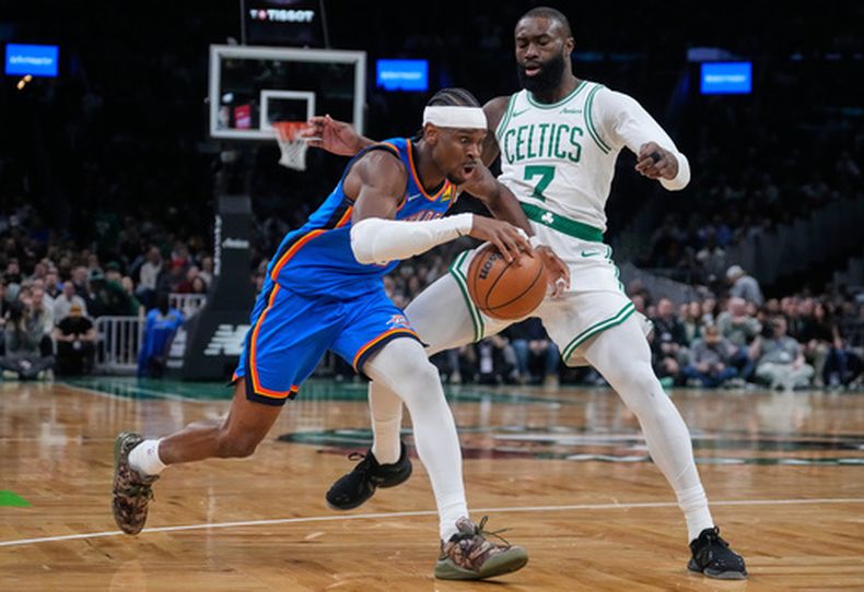 El base de los Thunder de Oklahoma City, Shai Gilgeous-Alexander (izquierda), se dirige hacia la canasta ante el base de los Celtics de Boston, Jaylen Brown (7), durante la primera mitad de un juego de baloncesto de la NBA, el miércoles 25 de marzo de 2026, en Boston. (Foto AP/Charles Krupa)