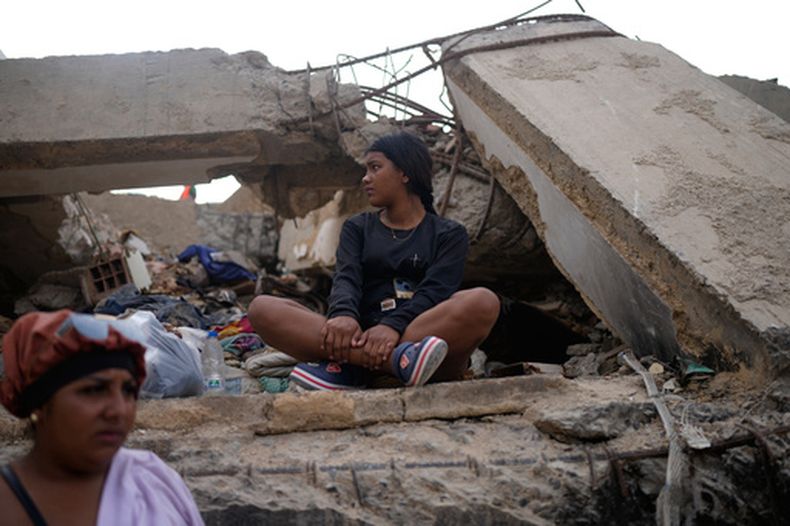 Fabiana Jaimes está sentada junto a un edificio derrumbado por los terremotos mientras espera a que los trabajadores terminen de retirar los escombros en la búsqueda incesante de su madre, Yalizca Bravo, en La Guaira, Venezuela, el jueves 23 de julio de 2026. (Foto AP/Ariana Cubillos)