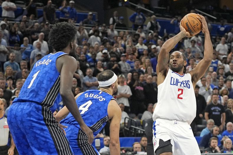 Kawhi Leonard, de los Clippers de Los Ángeles, dispara frente a Jonathan Isaac y Jalen Suggs, del Magic de Orlando, el viernes 29 de marzo de 2024 (AP Foto/John Raoux)