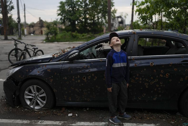 Un niño voltea a ver un edificio destruido debido a los ataques en Irpin, en las afueras de Kiev, Ucrania, el lunes 30 de mayo de 2022. (AP Foto/Natacha Pisarenko)