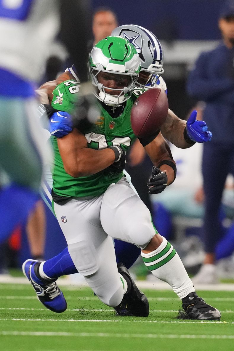 Saquon Barkley (26), corredor de los Eagles de Filadelfia, suelta el balón durante la segunda mitad del partido de la NFL en contra de los Cowboys de Dallas el domingo 23 de noviembre de 2025, en Arlington, Texas. El balón fue recuperado por Dallas. (AP Foto/Julio Cortez )