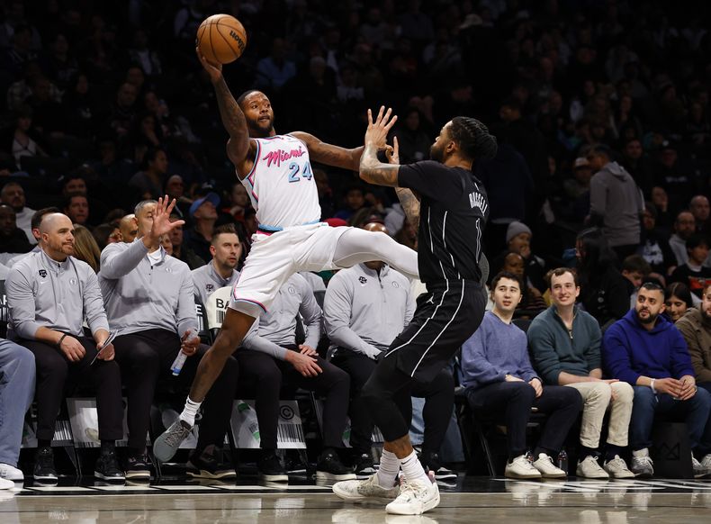 El alero del Heat de Miami Haywood Highsmith (24) mantiene el balón en juego contra el escolta de los Nets de Brooklyn DAngelo Russell (1) durante la primera mitad de un partido de baloncesto de la NBA, el sábado 25 de enero de 2025, en Nueva York. (AP Foto/Noah K. Murray)