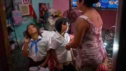Yurima Izaguirre prepara a dos de sus hijos para su regreso a clases utilizando la linterna de su teléfono celular para iluminar la habitación durante un apagón en Minas, en la provincia de La Habana, Cuba, el martes 1 de septiembre de 2026. (AP Foto/Ramón Espinosa)
