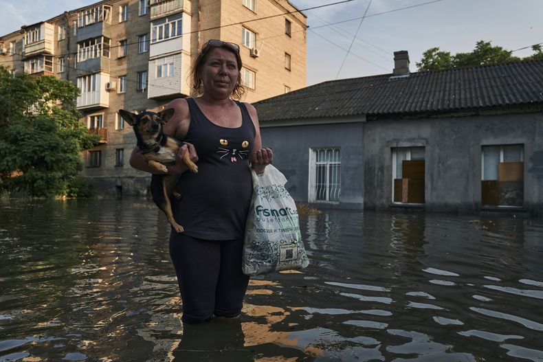 Una mujer camina por una calle inundada en Jersón, Ucrania, el martes 6 de junio de 2023. (AP Foto/Libkos)