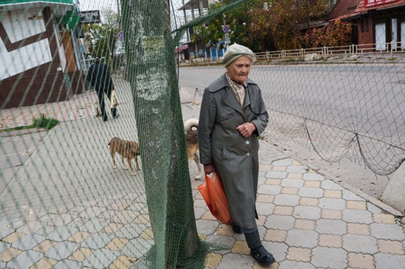 Una mujer mayor pasa junto a redes antidrones instaladas en una calle durante un alto el fuego relacionado con la evacuación de Oleshky, en Jersón, Ucrania, el 27 de octubre de 2026. (AP Foto/Evgeniy Maloletka)