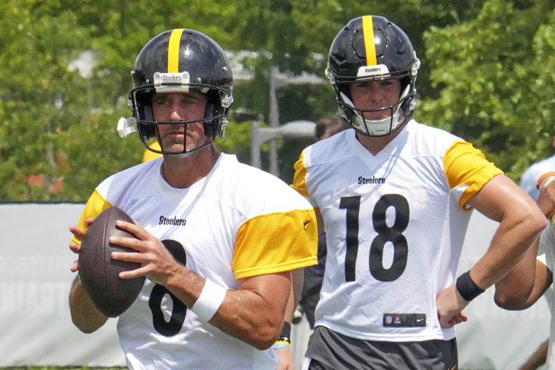 El quarterback de los Steelers de Pittsburgh, Aaron Rodgers (8), busca a quién pasarle el balón mientras el quarterback de los Steelers de Pittsburgh, Will Howard (18), espera su turno durante la práctica en el campamento de entrenamiento de fútbol americano de la NFL en Latrobe, Pensilvania, el sábado 26 de julio de 2025. (AP Photo/Gene J. Puskar)