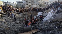 Palestinos reunidos en torno a los restos de una casa destruida tras ataques israelíes en Ciudad de Gaza, Franja de Gaza, el sábado 21 de octubre de 2023. (AP Foto/Abed Khaled)