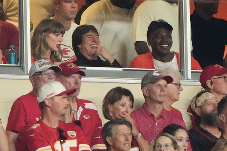Taylor Swift, izquierda, sentada junto a Tom Cruise, centro, mientras observan la primera mitad de un partido de la NFL entre los Chiefs de Kansas City y los Broncos de Denver, el lunes 14 de septiembre de 2026, en Kansas City, Misuri. (Foto AP/Charlie Riedel)