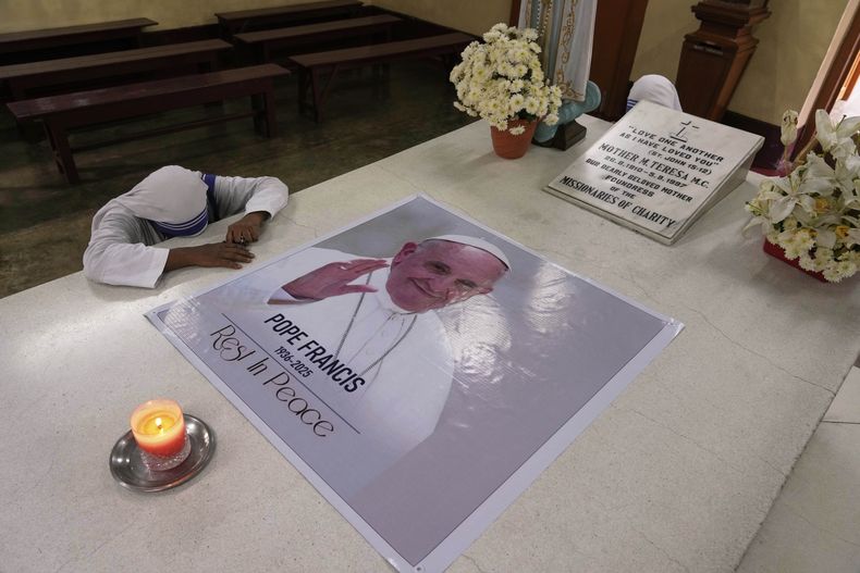 Una monja de la orden católica Misioneras de la Caridad, fundada por Santa Teresa de Calcuta, reza junto a un retrato del papa Francisco, colocado sobre la tumba de la santa luego de su muerte, en Calcuta, India, el 22 de abril de 2025. (AP Foto/Bikas Das)