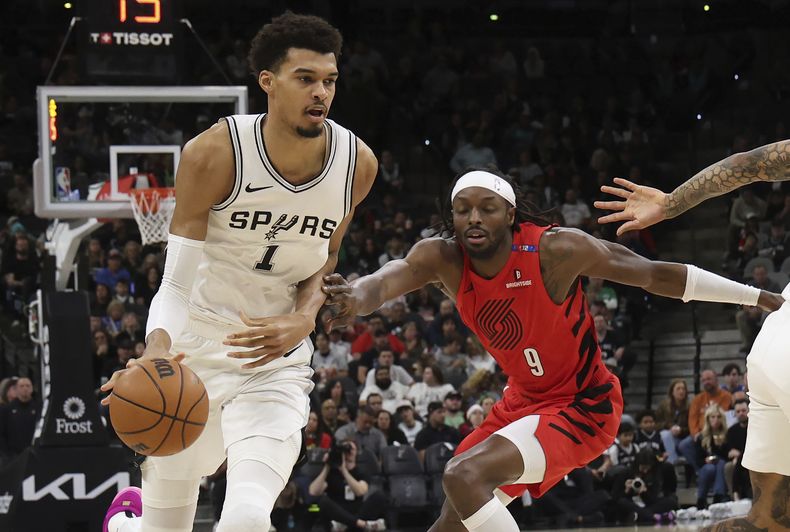 El francés Victor Wembanyama, de los Spurs de San Antonio, conduce el balón frente a Jerami Grant, de los Trail Blazers de Portland, el sábado 21 de diciembre de 2024 (AP Foto/Kin Man Hui)