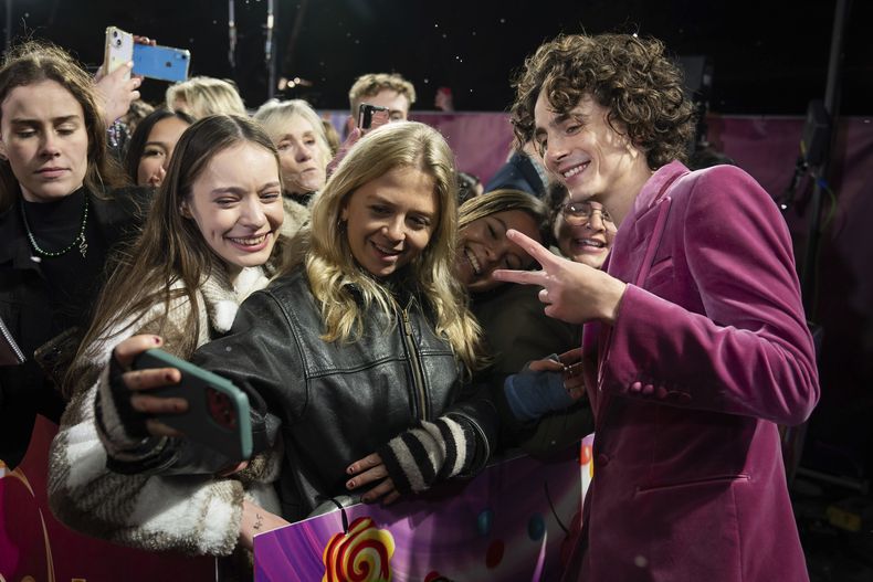 Timothee Chalamet, derecha, posa para retratos con fans a su llegada a la premiere mundial de la película Wonka el martes 28 de noviembre de 2023 en Londres. (Scott Garfitt/Invision/AP)