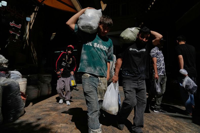 Dos personas cargan paquetes en el histórico Gran Bazar de Teherán, Irán, el 1 de junio de 2026. (AP Foto/Vahid Salemi)
